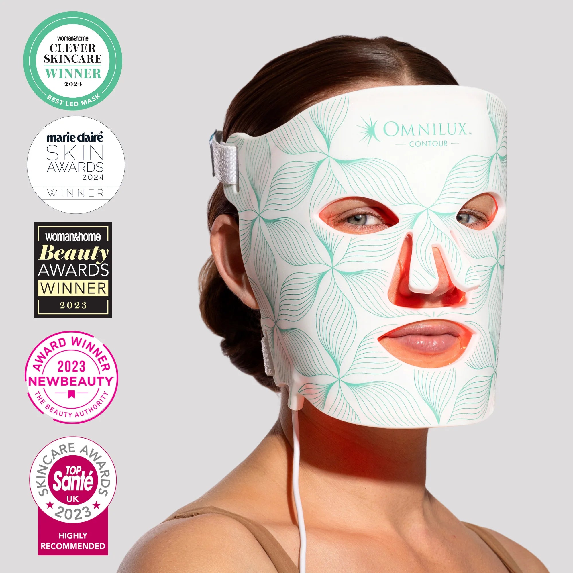 Woman wearing a LED face mask with multiple award badges on a light gray background