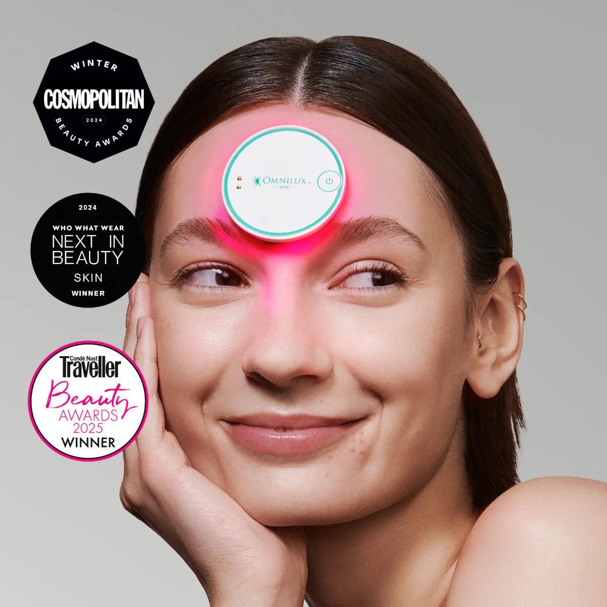 Woman using a skincare device with awards displayed around her.